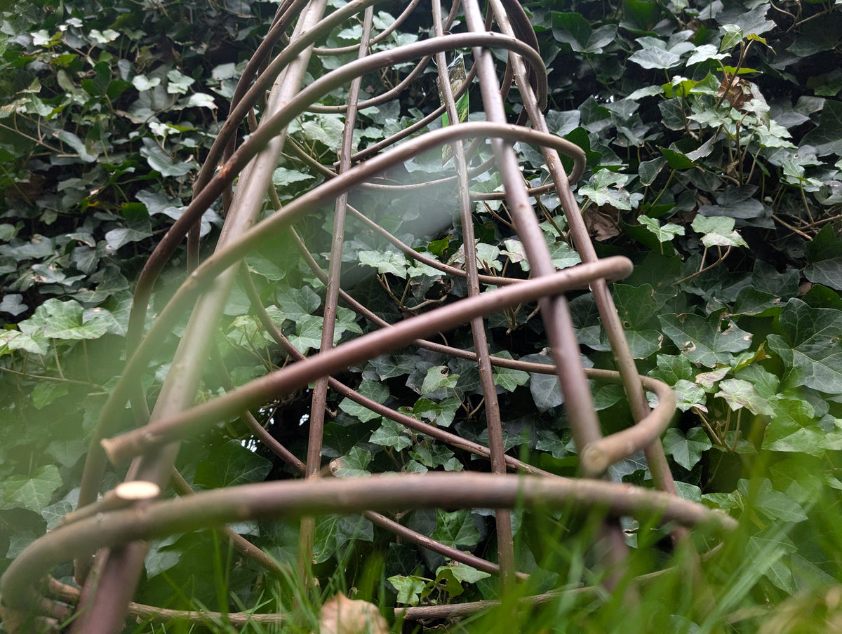 Detail van een gevlochten plantensteun tussen groen